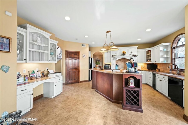 kitchen with arched walkways, built in desk, open shelves, a sink, and dishwasher