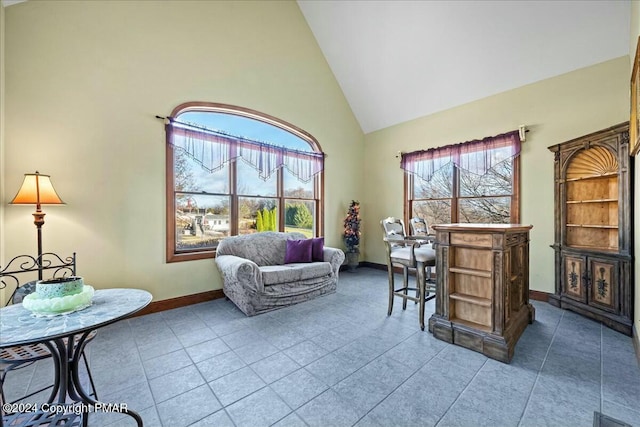 interior space with a healthy amount of sunlight, baseboards, and high vaulted ceiling