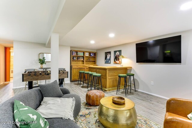 living area featuring a dry bar, light wood-style floors, baseboards, and recessed lighting