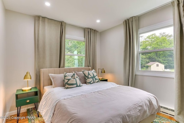 bedroom featuring baseboards, baseboard heating, wood finished floors, and recessed lighting