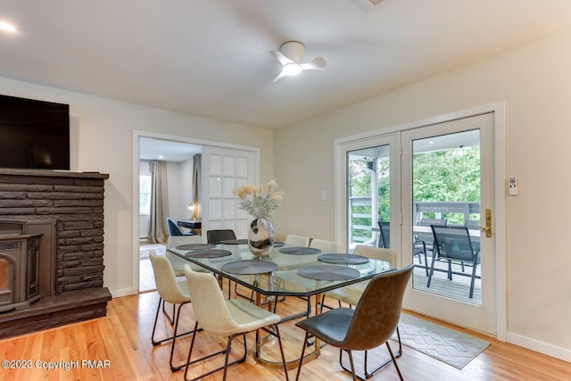 dining area with light wood finished floors, a wood stove, and baseboards