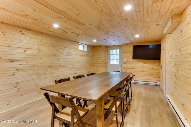 dining space with a baseboard radiator, wooden ceiling, wooden walls, baseboard heating, and light wood finished floors