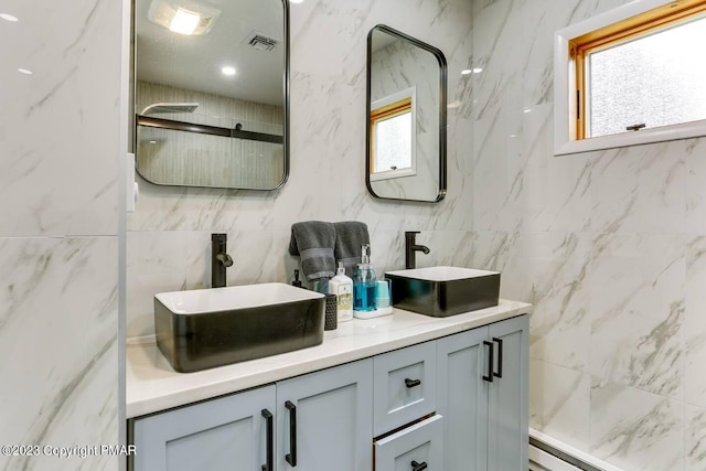 full bathroom with a wealth of natural light, visible vents, a sink, and double vanity