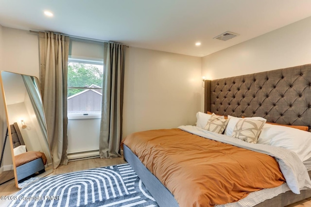 bedroom featuring a baseboard heating unit, wood finished floors, visible vents, and recessed lighting