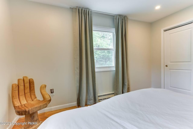 bedroom featuring a baseboard heating unit, recessed lighting, baseboards, and wood finished floors