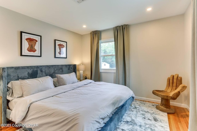 bedroom with recessed lighting, wood finished floors, and baseboards