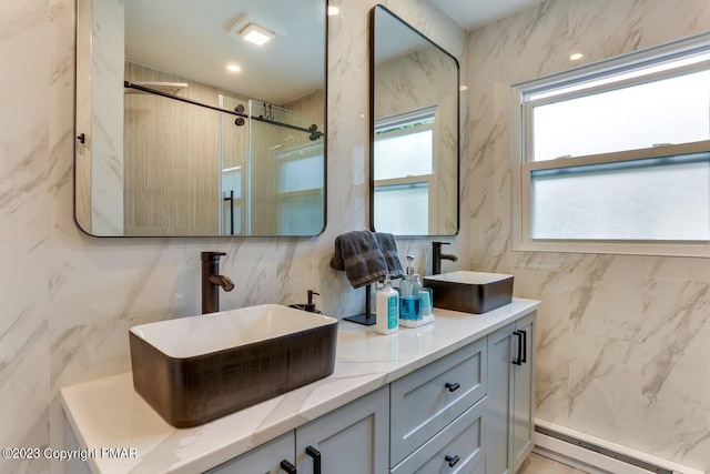 bathroom featuring a baseboard heating unit, double vanity, a sink, and tile walls