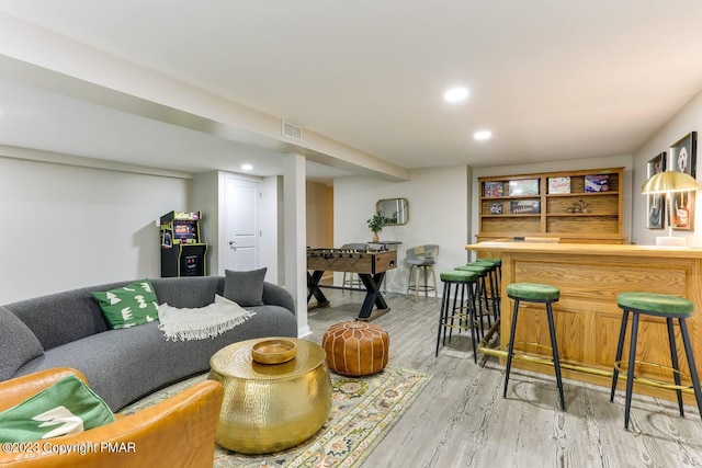 living room with recessed lighting, visible vents, light wood-style flooring, and a bar