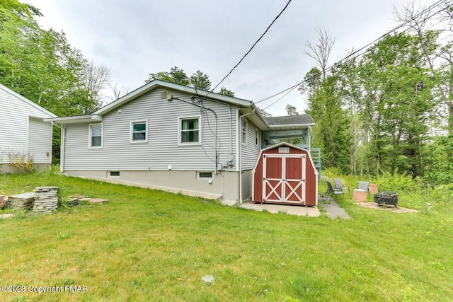 rear view of house featuring a storage shed, an outdoor fire pit, a lawn, and an outdoor structure