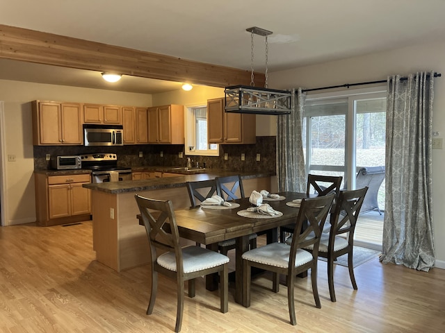 dining room featuring beam ceiling, baseboards, light wood finished floors, and a toaster