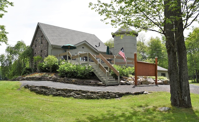 back of house with a yard, stone siding, stairway, roof with shingles, and a wooden deck