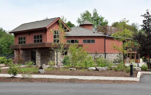 view of front facade with stone siding and roof with shingles