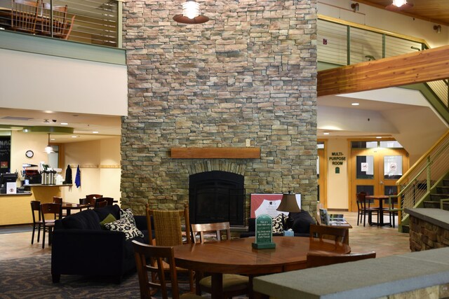 living area with a stone fireplace, stairway, and a high ceiling