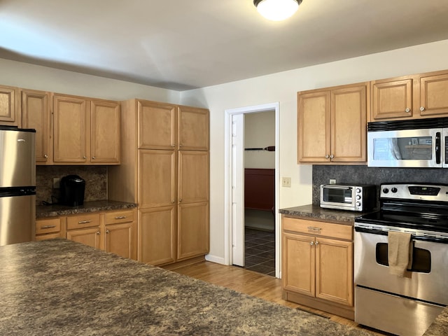 kitchen featuring stainless steel appliances, dark countertops, decorative backsplash, and a toaster