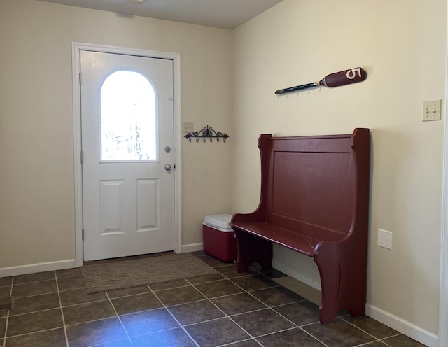 mudroom with dark tile patterned floors and baseboards