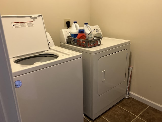 laundry area with laundry area, baseboards, washer and clothes dryer, and dark tile patterned flooring