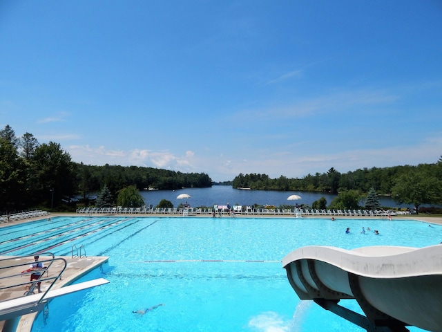 community pool with a water view, a wooded view, and a diving board