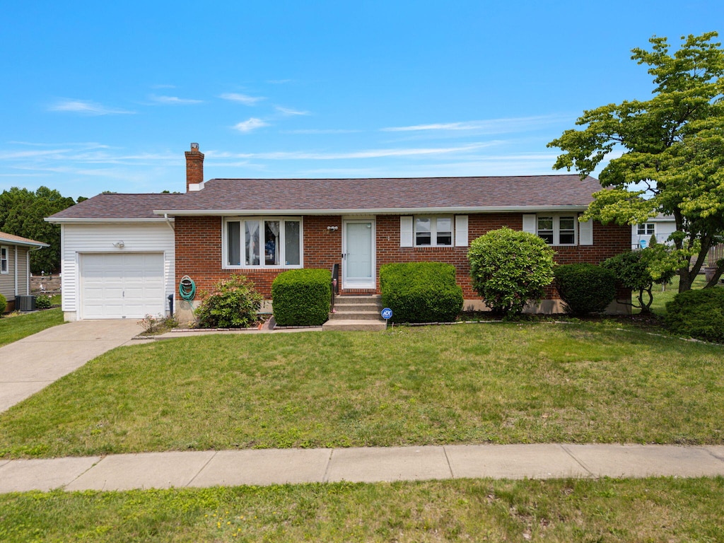 94 Brader Dr, Wilkes Barre, PA 18705 - ranch-style home with an attached garage, a chimney, driveway, a front lawn, and brick siding