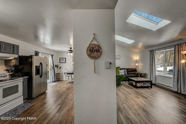 kitchen featuring white electric stove, lofted ceiling with skylight, dark hardwood / wood-style floors, and stainless steel fridge