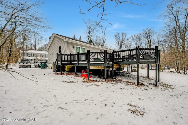 snow covered rear of property with a deck