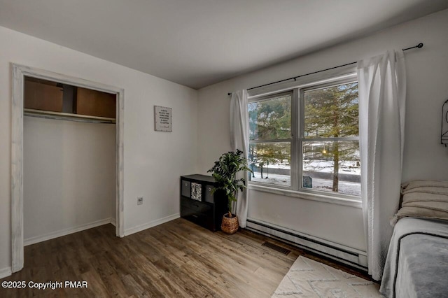 unfurnished bedroom featuring hardwood / wood-style flooring, a closet, and a baseboard heating unit