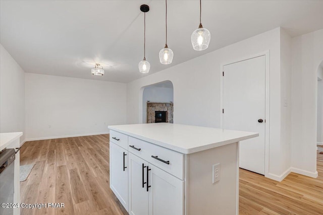 kitchen with arched walkways, light countertops, and light wood finished floors