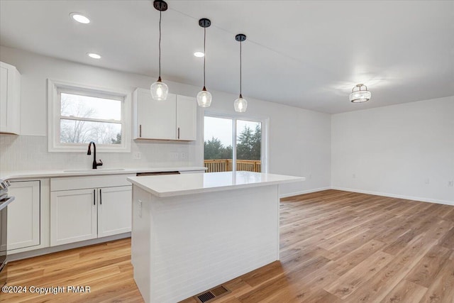 kitchen with light countertops, light wood finished floors, a sink, and a healthy amount of sunlight