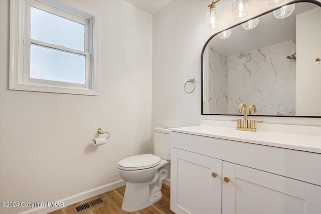 bathroom featuring baseboards, visible vents, toilet, wood finished floors, and vanity