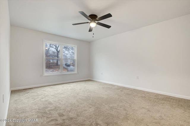 carpeted empty room featuring visible vents, ceiling fan, and baseboards