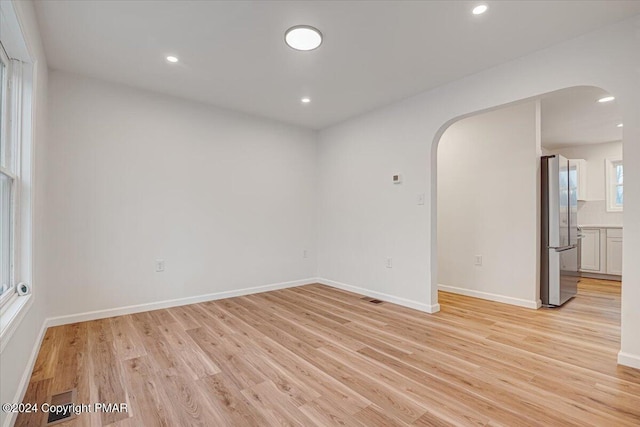 spare room featuring light wood-style floors, arched walkways, and recessed lighting