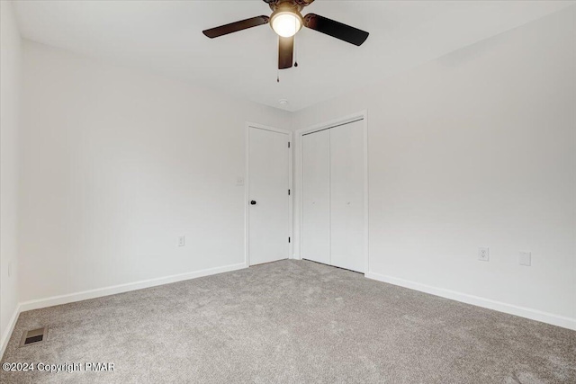 carpeted empty room featuring baseboards, visible vents, and a ceiling fan