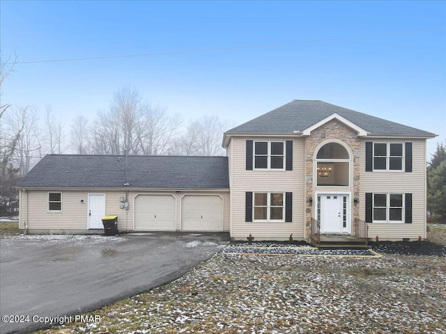 view of front facade featuring driveway, stone siding, a garage, and roof with shingles