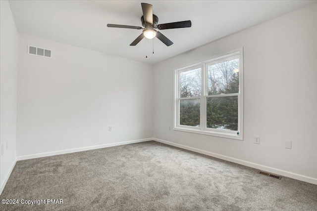 carpeted empty room with ceiling fan, visible vents, and baseboards