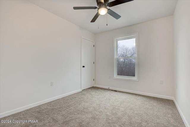 carpeted empty room featuring ceiling fan and baseboards