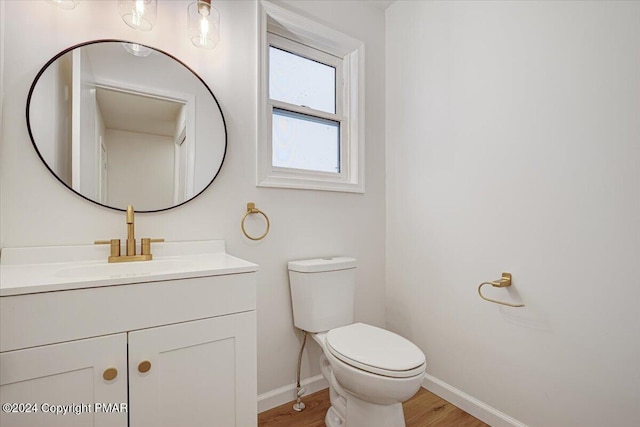 bathroom featuring baseboards, vanity, toilet, and wood finished floors