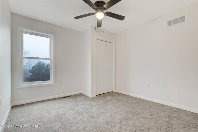 empty room with carpet, visible vents, ceiling fan, and baseboards