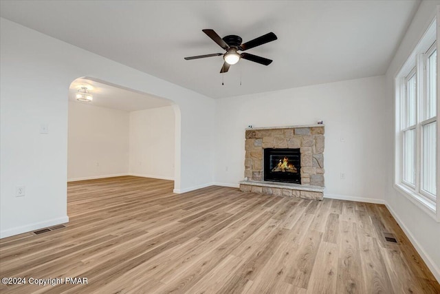 unfurnished living room featuring light wood-type flooring, visible vents, and arched walkways