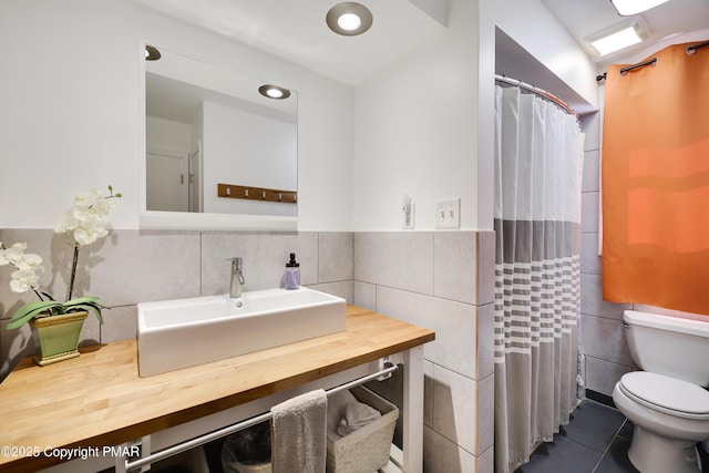 bathroom featuring walk in shower, tile patterned floors, toilet, tile walls, and vanity