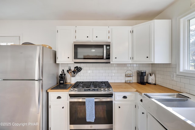 kitchen featuring appliances with stainless steel finishes, sink, white cabinets, and backsplash