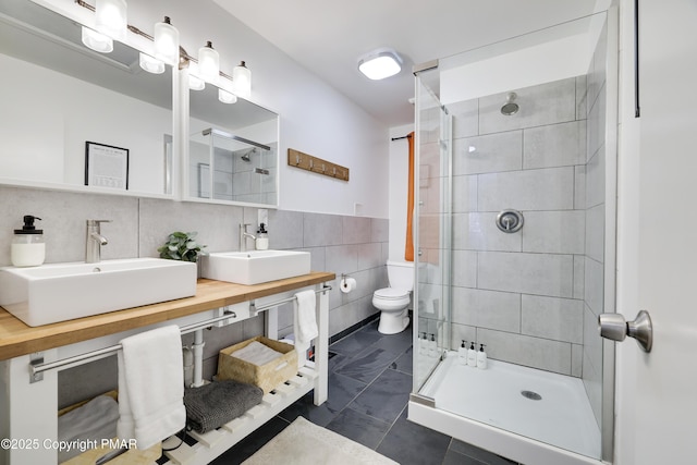 bathroom with tile walls, sink, toilet, and a tile shower