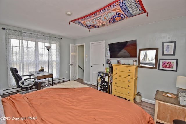 bedroom with baseboards, baseboard heating, and wood finished floors