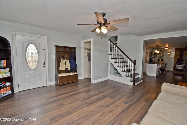 foyer entrance featuring a ceiling fan, wood finished floors, baseboards, and stairs