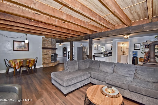 living area with a stone fireplace, wood finished floors, wooden ceiling, beamed ceiling, and baseboards