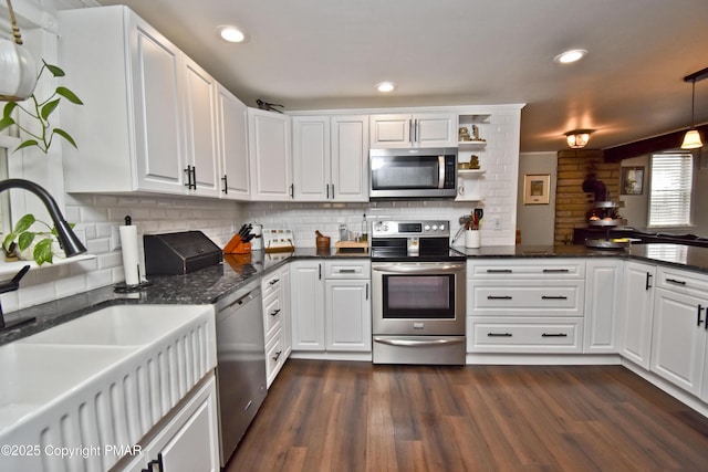 kitchen featuring appliances with stainless steel finishes, dark wood-type flooring, a sink, and white cabinetry