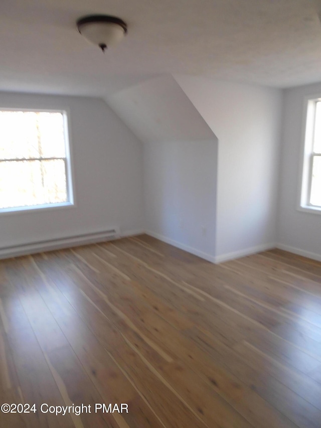 additional living space with vaulted ceiling, wood finished floors, and baseboard heating