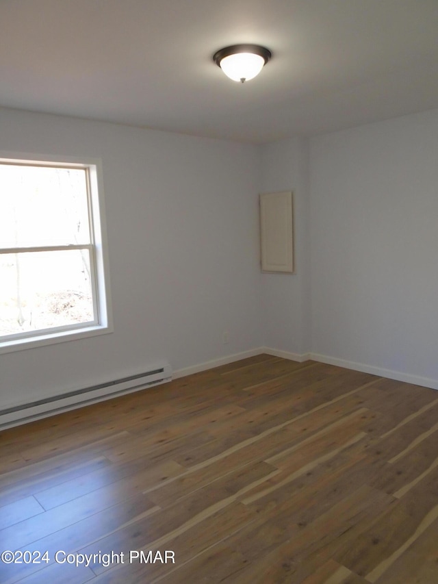 unfurnished room with hardwood / wood-style flooring, baseboards, and a baseboard radiator