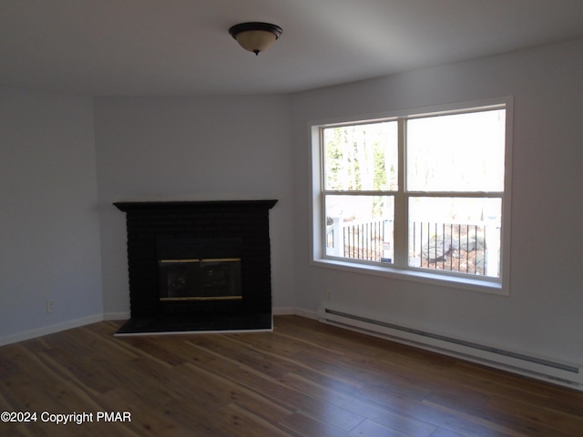 unfurnished living room with a glass covered fireplace, wood finished floors, baseboards, and a baseboard radiator