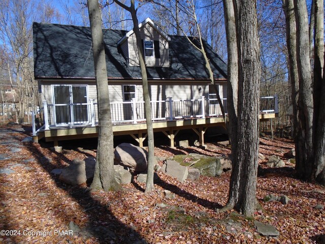 rear view of property with a deck and roof with shingles