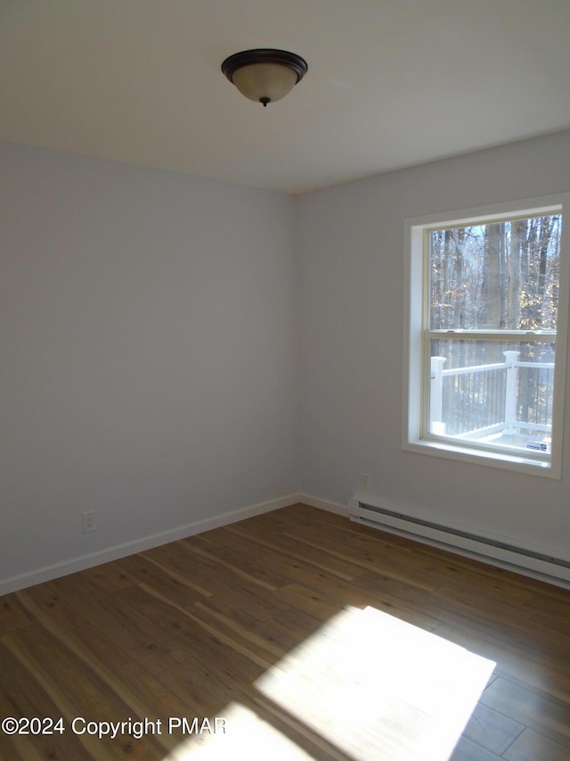 spare room with a baseboard heating unit, wood finished floors, and baseboards