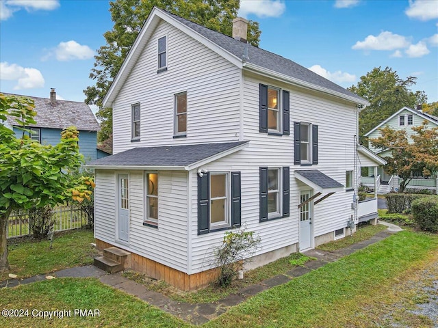 view of side of home with entry steps, fence, a chimney, and a lawn